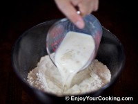 Pour warm milk mixed with sugar and dry yeast to bowl with flour